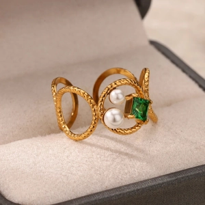 Dettaglio di un anello dorato vintage con gemma verde quadrata e perle bianche in scatola
