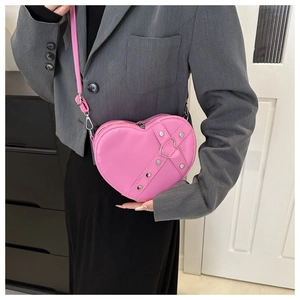 Detail van roze hartvormige schoudertas met zilveren studs op grijs blazer model