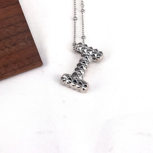 Macro detail of silver letter I pendant with stud texture on dainty beaded chain
