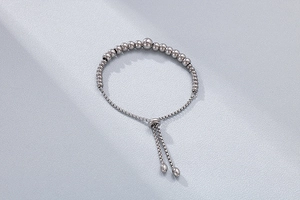 Detail of silver beaded bracelet featuring adjustable slide closure and gradient metal beads