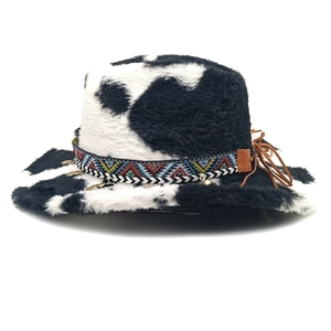 Detail of plush cow print hat with ethnic embroidered band and gold leaf pendants