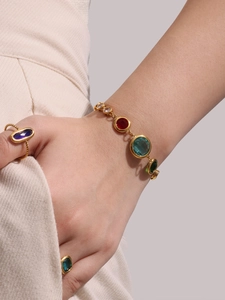 Detail view of gold bohemian bracelet and oval ring set with multi-color gemstones