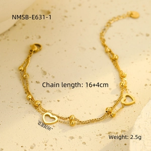 Close-up of golden double-layer bracelet with heart pendant and bead detailing