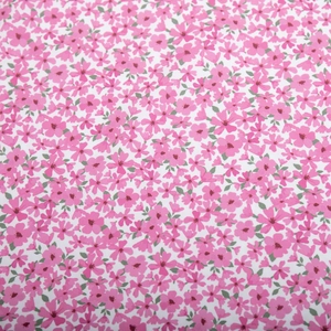 Close-up of pink floral print pattern on summer dress fabric with green leaf details