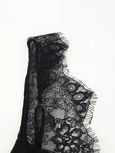 Close-up of delicate black eyelash lace fabric showing floral embroidery and mesh detail