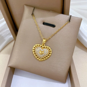 Detailed close-up of a hollow heart pendant with sparkling crystals on a gold chain
