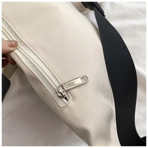 Close-up of white crossbody bag fabric texture with silver metal zipper and black strap