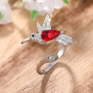 Detailopname van een verstelbare zilveren kolibrie ring met een rode druppelvormige steen