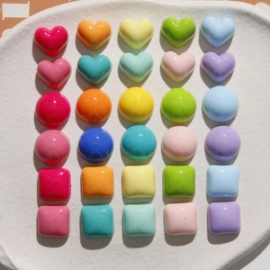 Colorful pastel resin heart and round DIY jewelry charms on a white plate