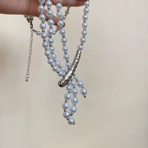 Macro shot of multilayered pearl necklace featuring asymmetrical silver metal accents