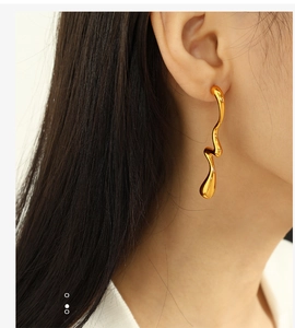 Close-up of elegant gold wavy earrings with high-gloss mirror finish for women