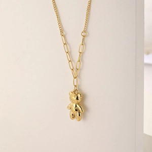 Golden bear pendant necklace with mixed paperclip chain design shown on a display stand