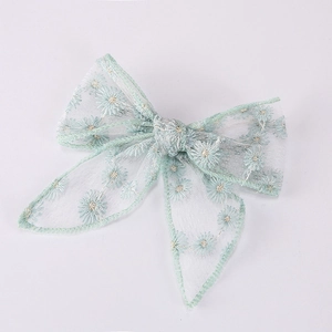 Close-up of light green mesh bow hair clip with detailed daisy flower embroidery
