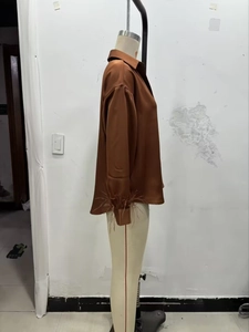 Detail of dark brown satin blouse showing textured sleeve cuffs with feather trim
