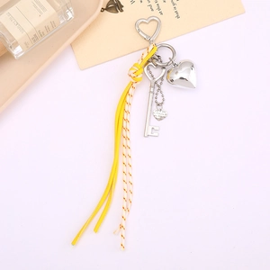 Détail du porte-clés en cuir tressé jaune avec breloques cœur et clip métallique
