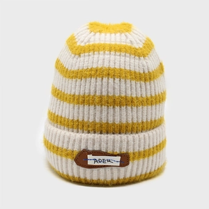 Detail of yellow and white striped knit beanie with ADER fabric patch and leather base