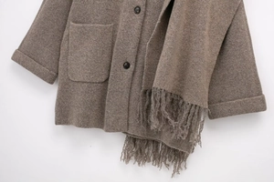 Detailed shot of knitted taupe coat featuring large patch pockets and tassel scarf