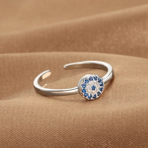 Silver Evil Eye open ring with blue and white cubic zirconia on brown textured background