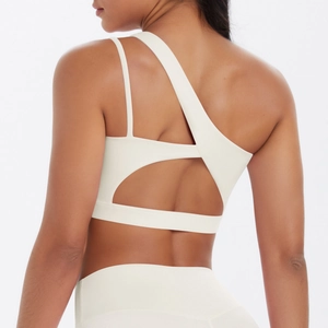 Detail of asymmetrical shoulder straps and open back cutout on cream yoga sports bra