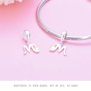 Detail of 925 sterling silver letter M charm with gold heart on a bracelet