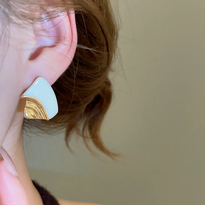 Detail view of a 18k gold plated geometric earring featuring cream resin on female model