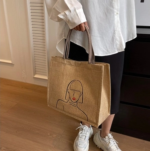 Detail of linen tote bag featuring minimalist line art and durable woven handles