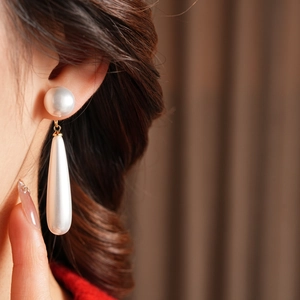 Close-up of model wearing elegant teardrop resin pearl earrings with golden metal links