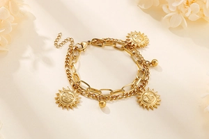 Detailed close-up of a double-layer gold sun pendant bracelet with Figaro chain links