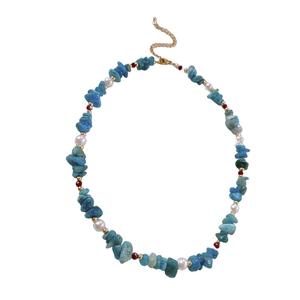 Aquamarine and pearl beaded necklace with red crystal accents on a white background