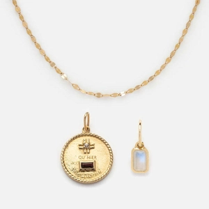 Detail of gold necklace with engraved French coin pendant and red gemstone charm