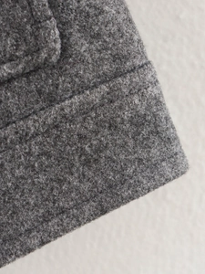 Nahaufnahme der dunkelgrauen Tweed-Stoffstruktur mit detaillierten Nähten für Herbstjacke