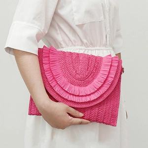 Detail of a pink woven raffia clutch bag with tiered fringe layers and envelope design