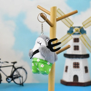 Funny shark plush keychain holding a black pitchfork and wearing green floral pants