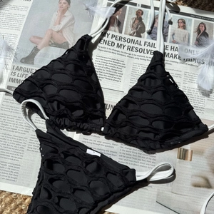 Détail du bikini noir avec texture en maille nid d'abeille, bretelles blanches et étiquette S
