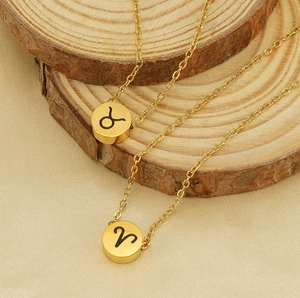 Dettaglio macro del ciondolo tondo dorato con segno zodiacale su superficie in legno