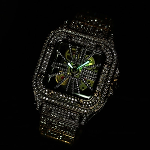 Close-up of gold iced-out square watch with skeleton dial and luminous hands