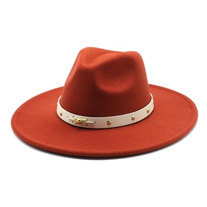 Detail of wool fedora hat with rust orange finish and studded leather band decor