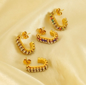 Macro detail of gold-plated U-shaped earrings featuring vibrant rainbow-colored zirconias