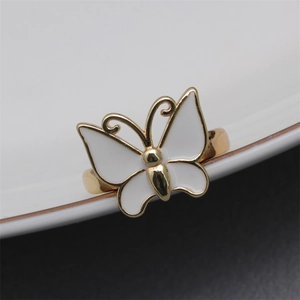 Macro detail of adjustable butterfly ring featuring gold plating and white enamel finish