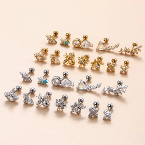Set of surgical steel stud earrings with zircons in gold and silver on pink background