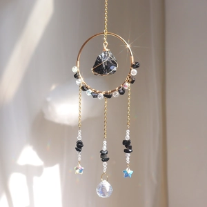 Detailed suncatcher with gold ring, raw black stone, blue star, and crystal drop