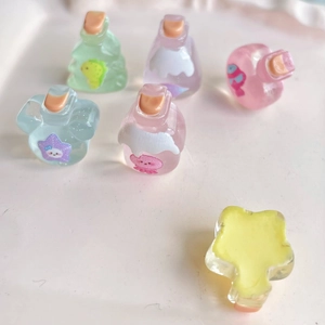 Miniature resin drift bottles and yellow star charms for DIY accessories on pink background