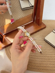 Detail of vintage ladies' oval watch with double-strand pearl strap and gold-tone case