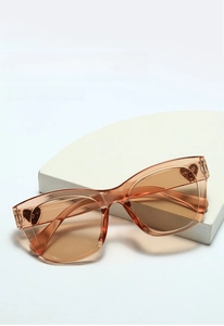 Detailed close-up view of stylish tea-colored heart-detail sunglasses on a white block