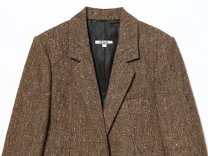 Detail of brown herringbone tweed blazer showing lapel texture and shoulder padding