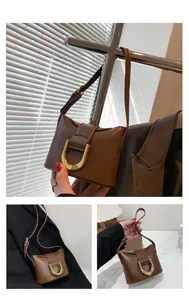 Detail of vintage brown leather handbag featuring a prominent gold U-shaped metal buckle
