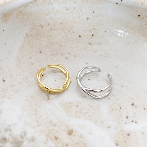 Close-up of irregular 925 sterling silver rings in gold and silver finish on a ceramic plate