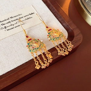 Détail de boucles d'oreilles cœur triangle en or 18 carats avec pompons et perles