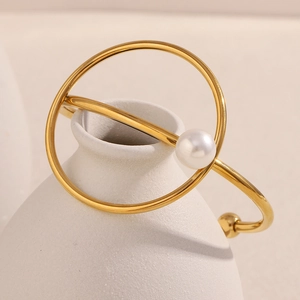 Detail of 18K gold plated bangle featuring a white pearl on a geometric ring design
