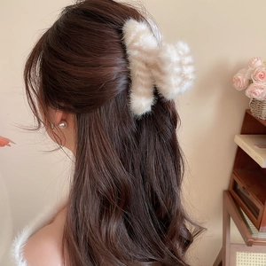 Détail d'une pince à cheveux en peluche rayée fixant de longs cheveux ondulés